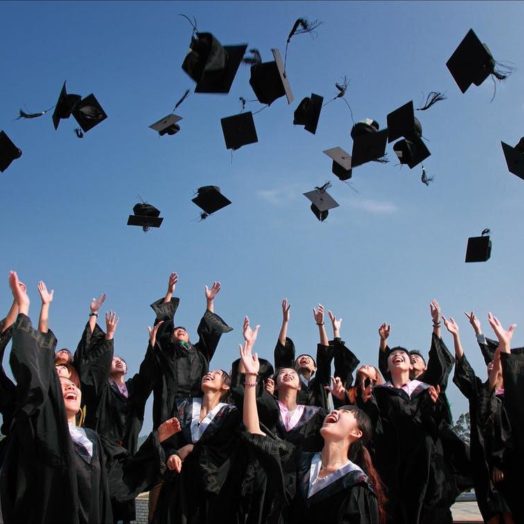 Newly Graduated People Wearing Black Academy Gowns Throwing Hats Up in the Air